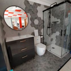 Expositor de baño con muebles, plato de ducha y sanitarios en interior de local